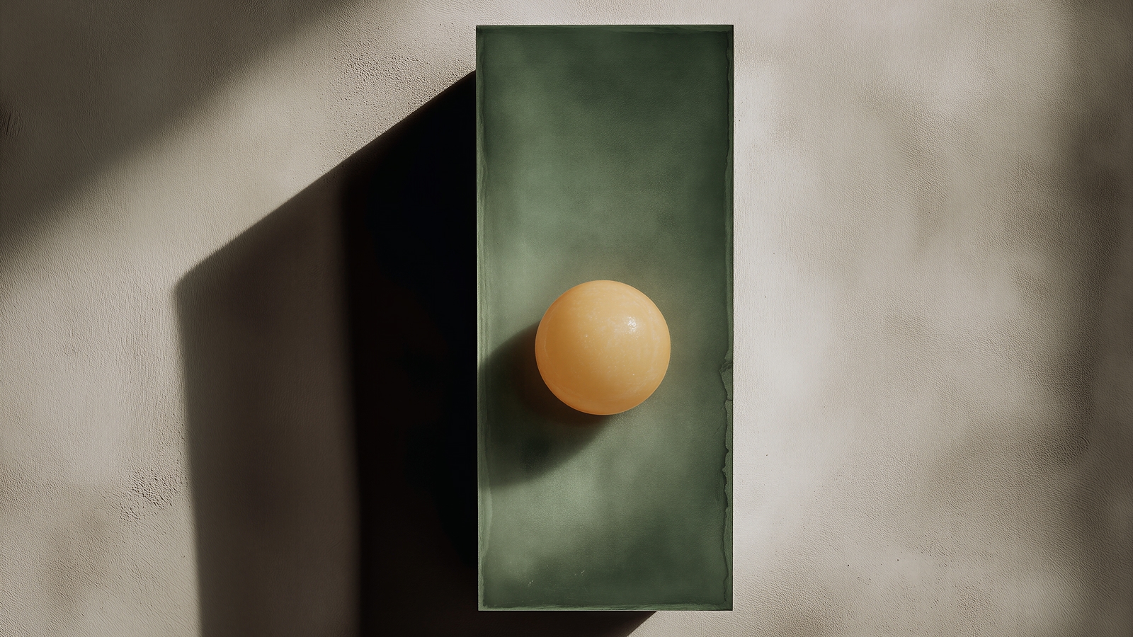 Pale orange sphere centred on a green stone slab casting a long shadow